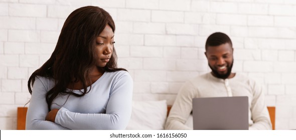 Couple Crisis Concept. Man Using Laptop, Not Paying Attention To Wife, Home Interior, Panorama