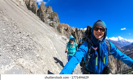 A Couple Crossing A Dangerous Passage Along The Landslide Area On The Way To Tilicho Base Camp, Annapurna Circus, Himalayas, Nepal. Dry And Desolated Landscape. Steep And Sharp Slopes. Danger