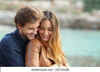 Couple Cuddling Affectionate On The Beach In Winter With The Sea In The Background