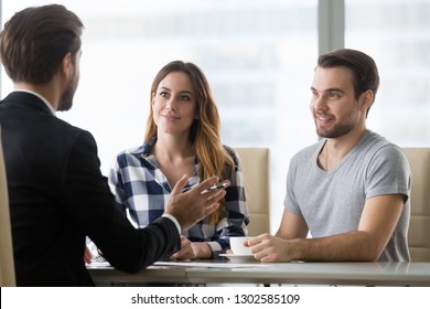 Couple customers consulting realtor lawyer or insurer about buying house or insurance services, salesman, bank worker or financial advisor making presentation offer to clients at meeting in office