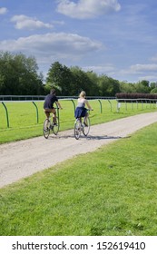 Couple Cycling On Cycle Track = Around Warwick Racecourse Park, Midlands, Uk