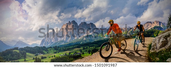 Couple\
cycling on electric bike, rides mountain trail. Woman and Man\
riding on bikes in Dolomites mountains landscape. Cycling e-mtb\
enduro trail track. Outdoor sport\
activity.