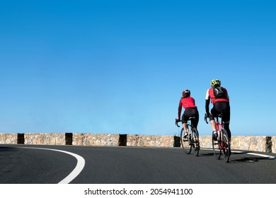 Couple of cyclists with a red 
T-shirt rides on the streets of Palma de Mallorca in a sunny day. Spain,Europe.