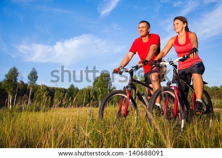 Couple of cyclists riding bicycles in meadow