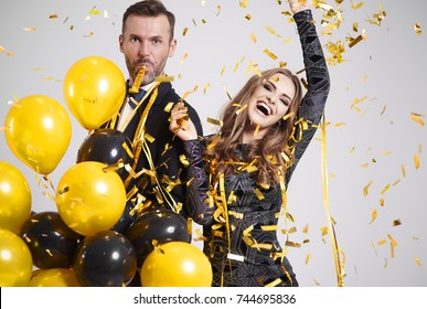 Couple dancing among falling confetti and streamer at party 
