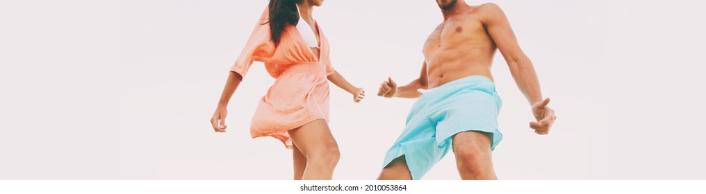 Couple dancing clubbing at beach party nightlife beachclub. Two young people wearing beachwear and shorts having fun on dance night. Lower body legs moving panoramic crop.