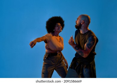 Couple Dancing Hip Hop Dance. Concept Of Contemporary Dancing. Idea Of Choreography. Young Cool Caucasian Man And Black Girl Isolated On Blue Background In Studio. Copy Space