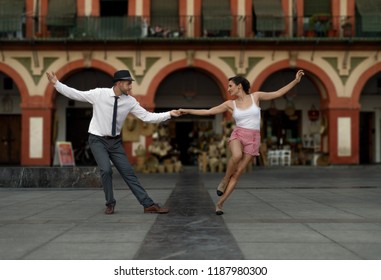 Couple dancing lindy hop happily in and spanish square.