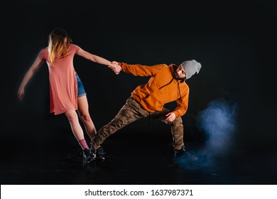 Couple dancing modern dance and showing off their leg stretch moves.Black background while the couple is dressed in urban colorful clothes. - Powered by Shutterstock