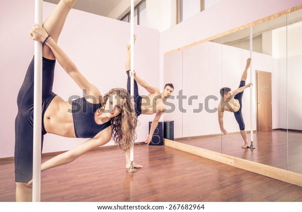 Couple\
dancing at pole in a fitness studio - Ballet dancers working out -\
Pole dancers looking at camera and stretching\
legs