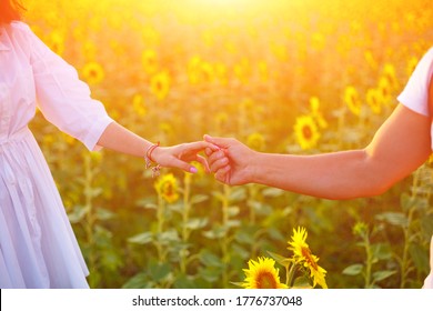 A couple dancing at sunset in a field with blooming sunflowers. Romantic relationships hold each other's hands