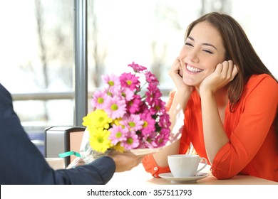 Couple Dating And Boyfriend Giving A Bouquet Of Flowers To His Candid Girlfriend In A Coffee Shop