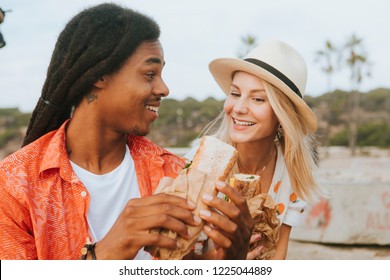 Couple dating and eating sandwiches at a beach picnic - Powered by Shutterstock