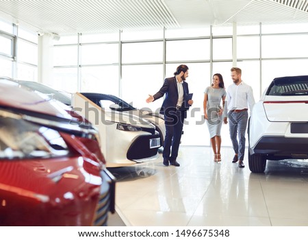 Couple and the dealer selling cars look the car in the showroom.
