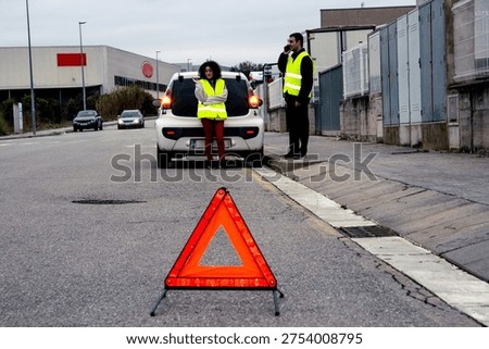 Couple dealing with car breakdown using warning triangle