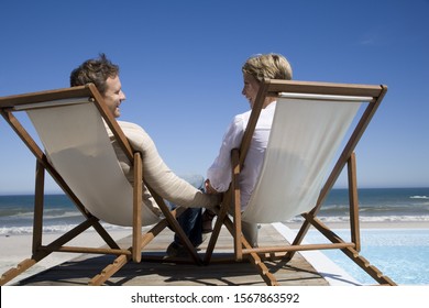 Couple In Deck Chairs Near Swimming Pool