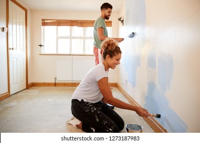 Couple Decorating Room In New Home Painting Wall Together