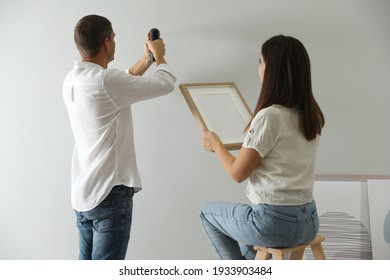 Couple Decorating Room With Picture Together. Interior Design