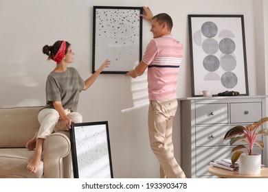 Couple decorating room with pictures together. Interior design