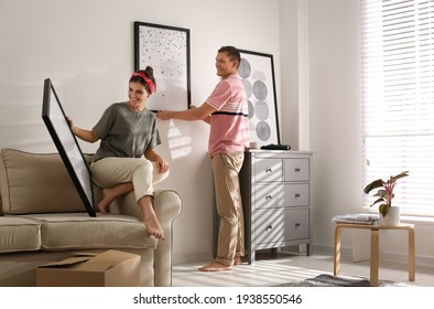 Couple Decorating Room With Pictures Together. Interior Design