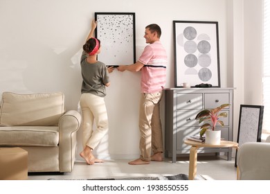Couple decorating room with pictures together. Interior design - Shutterstock ID 1938550555