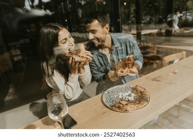 A couple delightfully indulges in slices of pizza at a charming café, surrounded by bright, airy ambiance and good vibes, savoring each bite together - Powered by Shutterstock