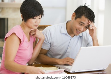 Couple In Dining Room With Laptop Looking Unhappy