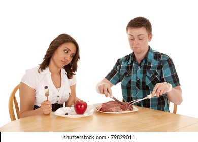 a couple with dinner and the woman is not happy with her fruit and the man has a huge steak.