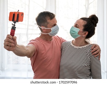 Couple In Disposable Masks Taking Selfie At Home. Social Distancing