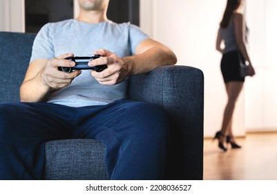 Couple In Distant Marriage. Man Playing Video Game Ignoring Woman. Lack Of Connection. Relationship Fight And Crisis. Lazy Husband On Couch, Sneaky Wife Leaving To Party. No Common Interests.