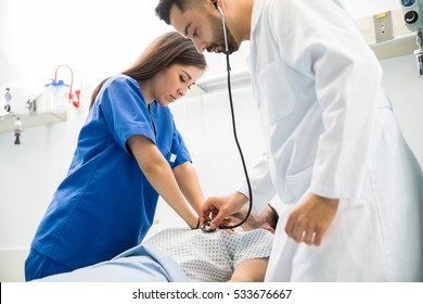 Couple Of Doctors Giving CPR To A Patient Lying On A Bed In The Emergency Room