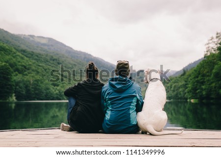 Couple with dog sitting on dock at the lake