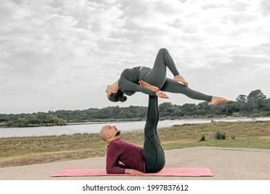 Couple doing acroyoga in a field and a lake - Powered by Shutterstock