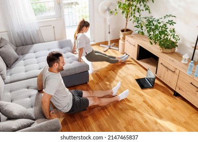 Couple Doing Online Workout Session At Home, Doing Triceps Dips On Living Room Couch