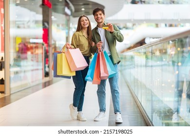Couple Doing Shopping Showing Credit Card Posing Standing Together And Smiling To Camera In Mall. Customers Advertising Mobile Banking Application Or Sales Offer. Full Length - Shutterstock ID 2157198025