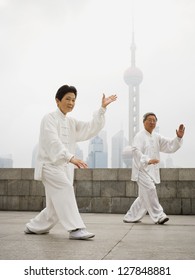 Couple Doing Tai Chi Outdoors With City Skyline In Background