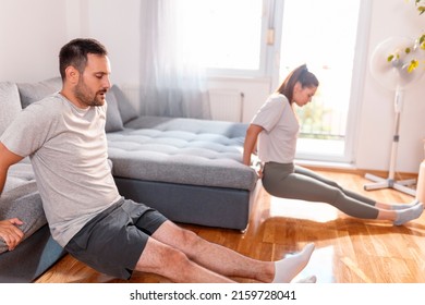 Couple Doing Triceps Dips On Living Room Couch While Working Out Together At Home