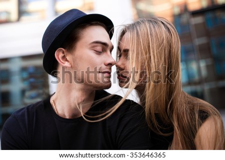 Couple dressed in black looking at each other, the guy wear black hat, a girl flying hair, close-up portrait