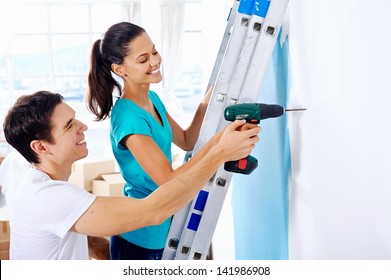 Couple Drilling In Wall Doing Diy At New Home After Moving In Together