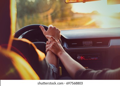 The couple drives the car on the way to the sunset. He drives the car, she holds his hand. Shooting close-up. Support for loved ones. Go to the sunset. Travel of lovers. - Powered by Shutterstock