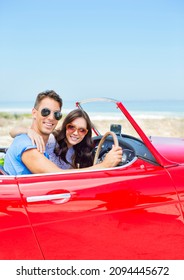 Couple Driving Convertible At Beach