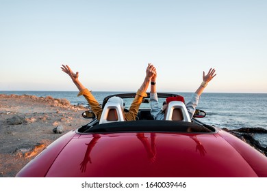 Couple driving convertible car, traveling near the ocean on a sunset, view from the backside. Happy vacations and traveling by car concept - Powered by Shutterstock