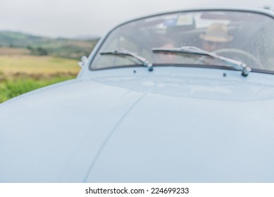 Couple Driving On A Vintage Car. Rain Drops On The Hood, Blurred Image