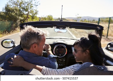 Couple driving in open top car look at each other, back view - Powered by Shutterstock