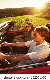 Couple Driving Vintage Convertible Car At Sunset