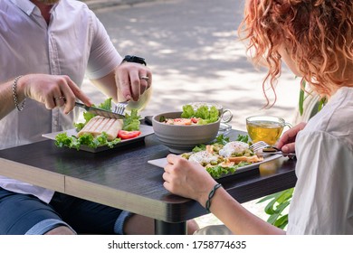 Couple Eating Lunch, Breakfast Or Brunch Outside The Cafe, Salad, Tea, Wrap, Waffles, Pouched Eggs