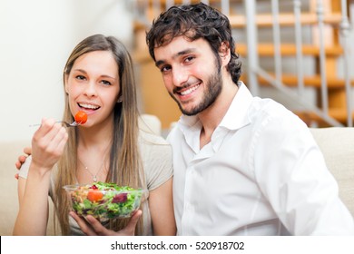 Couple Eating Salad On The Sofa