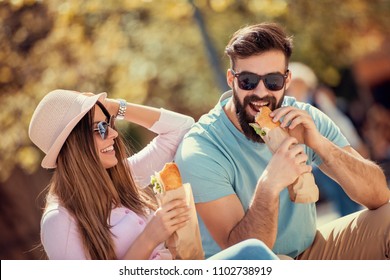 Couple eating sandwich outdoors,having great time together.