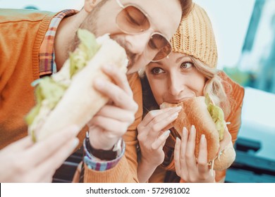 Couple eating sandwich and talking outdoor in the city.