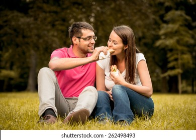 Couple Eating And Sharing Sandwich Outdoor In Nature